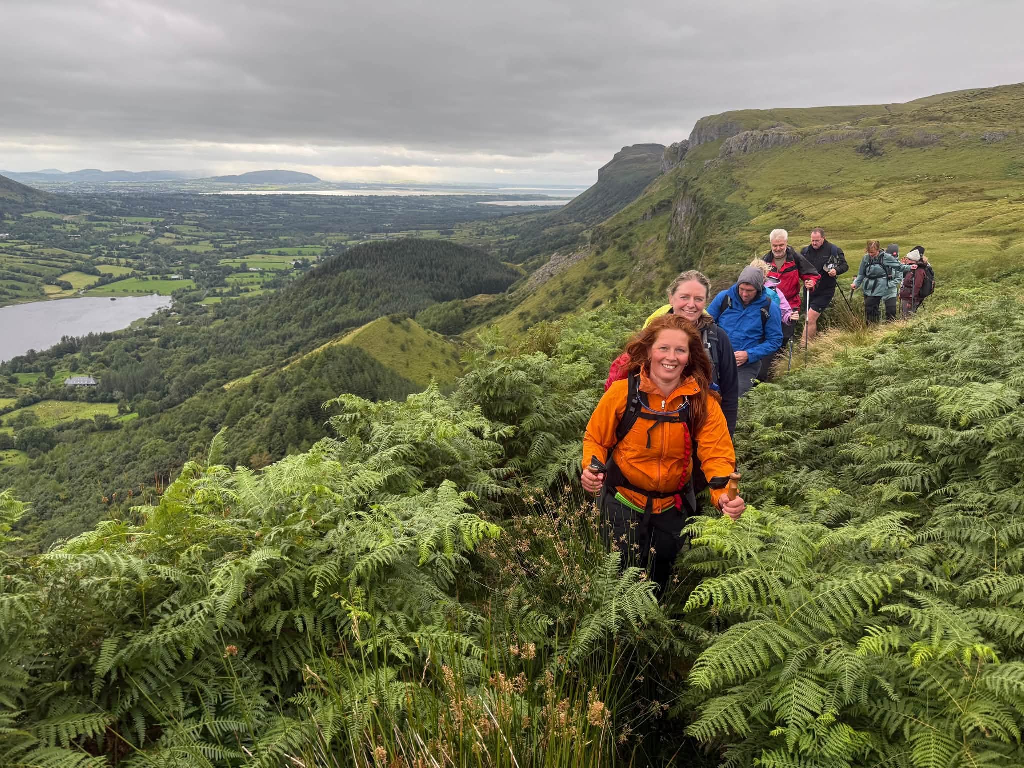 Andrea leading a group of walkers through green mountain landscape